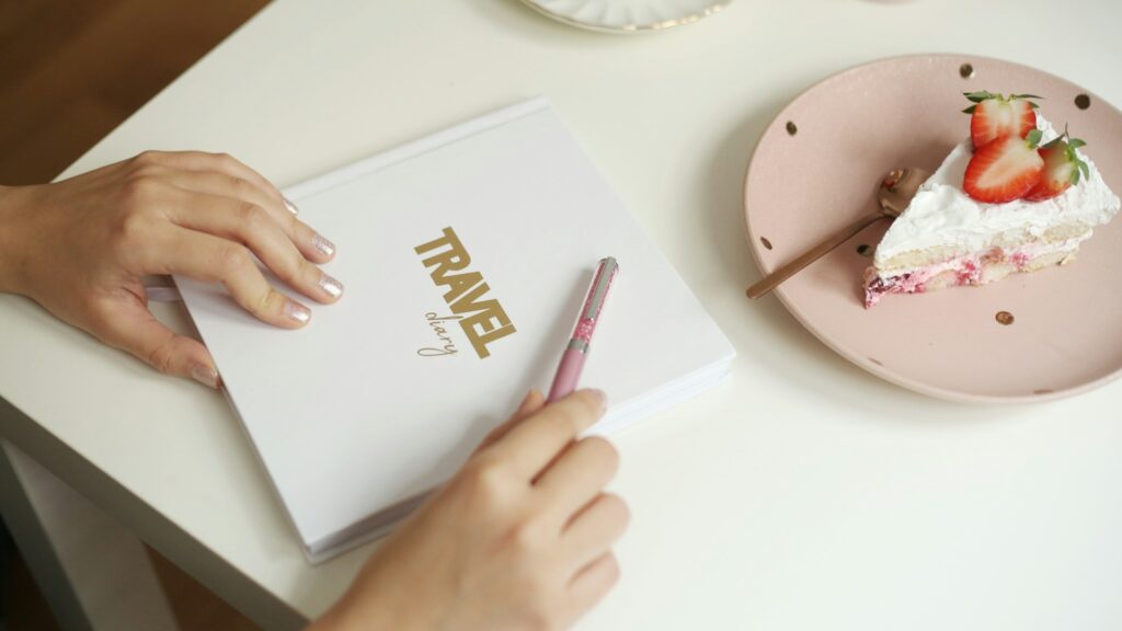 Mãos fechando guia de viagem ao lado de sobremesa, imagem que representa lifestyle, curadoria e assessoria de viagem personalizada