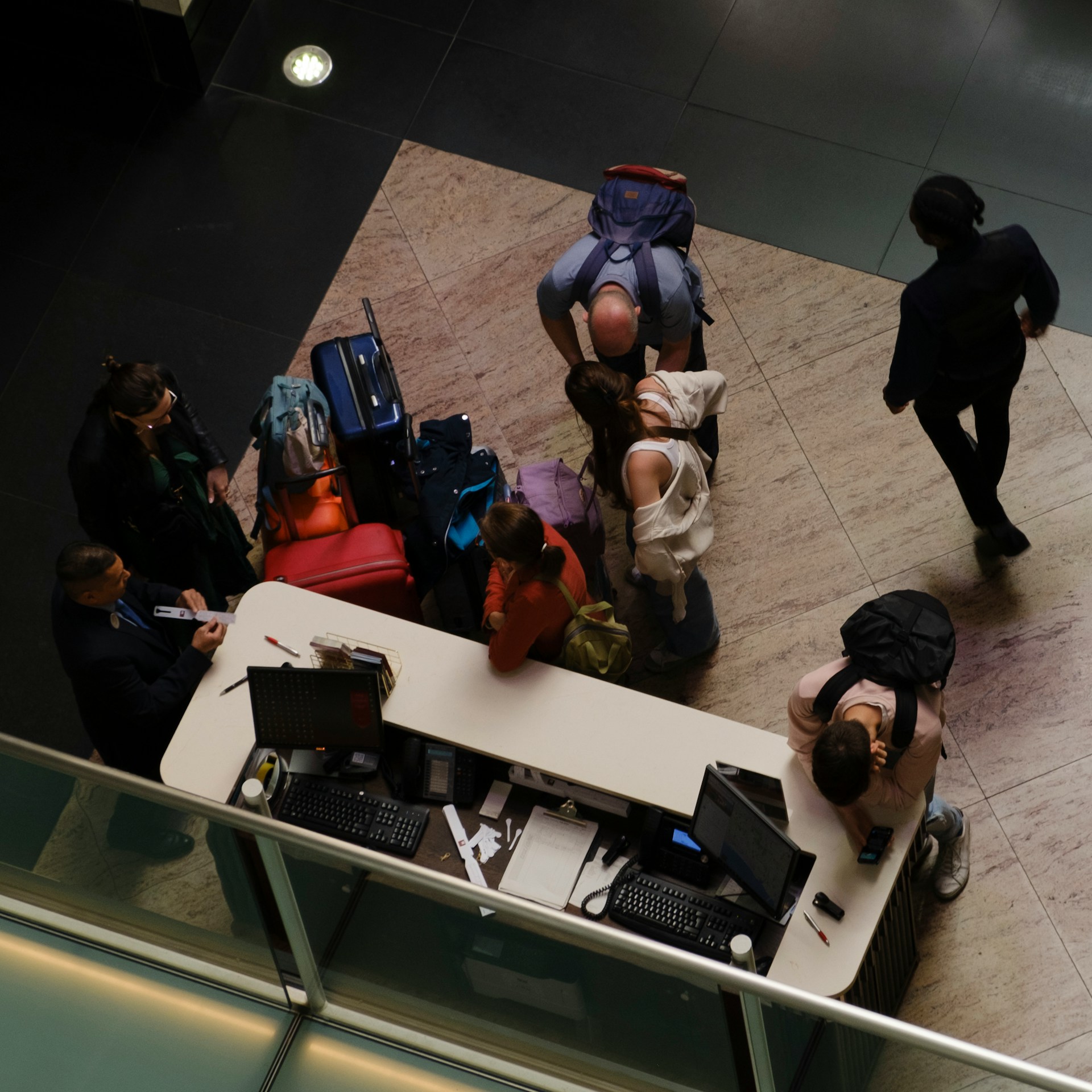 Vista superior de recepção com hóspedes e equipe, representando logística de chegada, hospitalidade e assessoria de viagem exclusiva