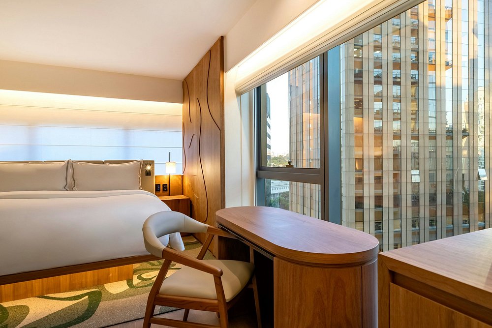 Quarto premium de canto no Westin Itaim Bibi, em São Paulo, com mesa de apoio junto à janela e vista urbana, ideal para viagem executiva e bleisure