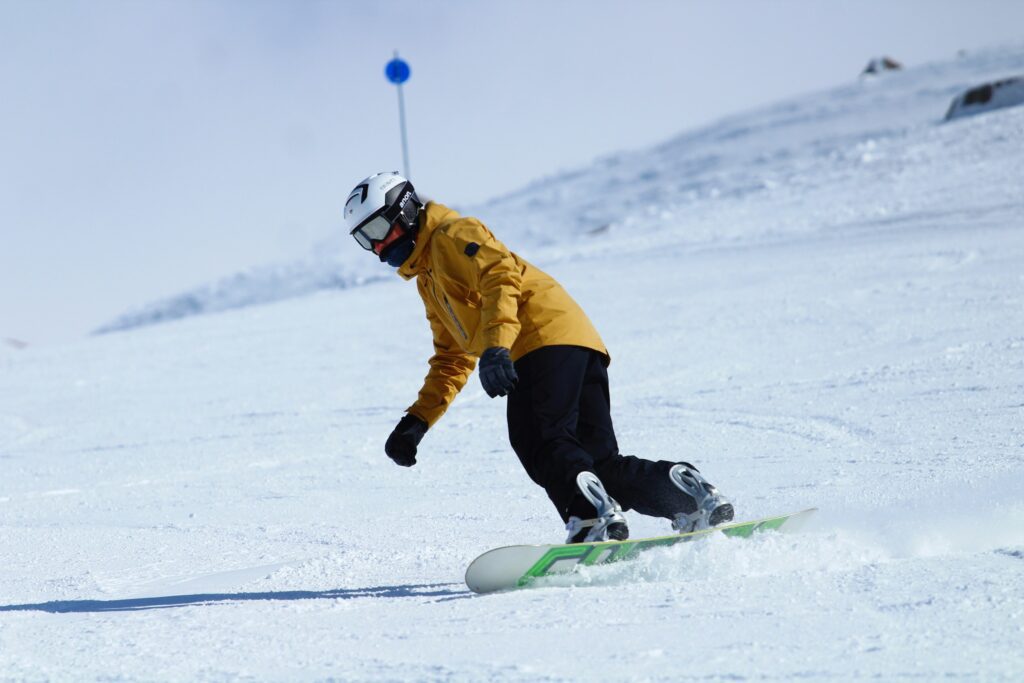 Homem praticando snowboard na neve em Bariloche. Conheça esse destino com Eloine Canato Assessoria. 